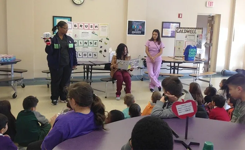 Members of the Times Square Family Dental team reading to a group of children at a local school.