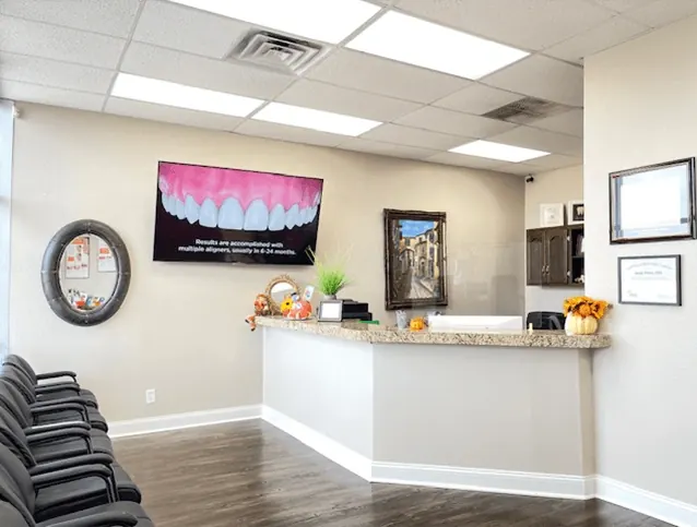 The curved reception desk at Times Square Family Dental, with framed art and a mirror on the wall.