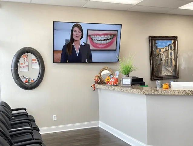 The reception desk at Times Square Family Dental, with a television in the waiting area.