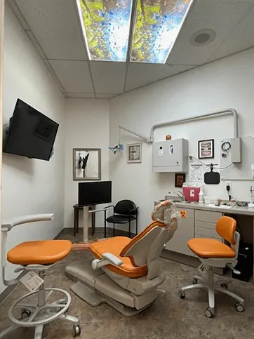 A bright treatment room at Times Square Family Dental with an orange chair.