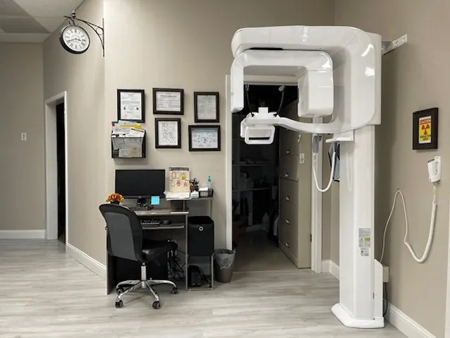 A panoramic X-ray unit in the hallway at Times Square Family Dental, beside a small office desk.